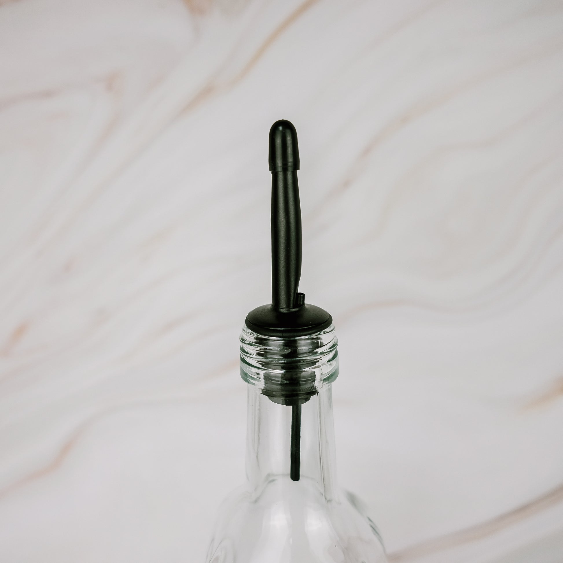 Black plastic pourer on glass oil bottle, ideal for kitchen storage and pantry organisation in NZ homes.