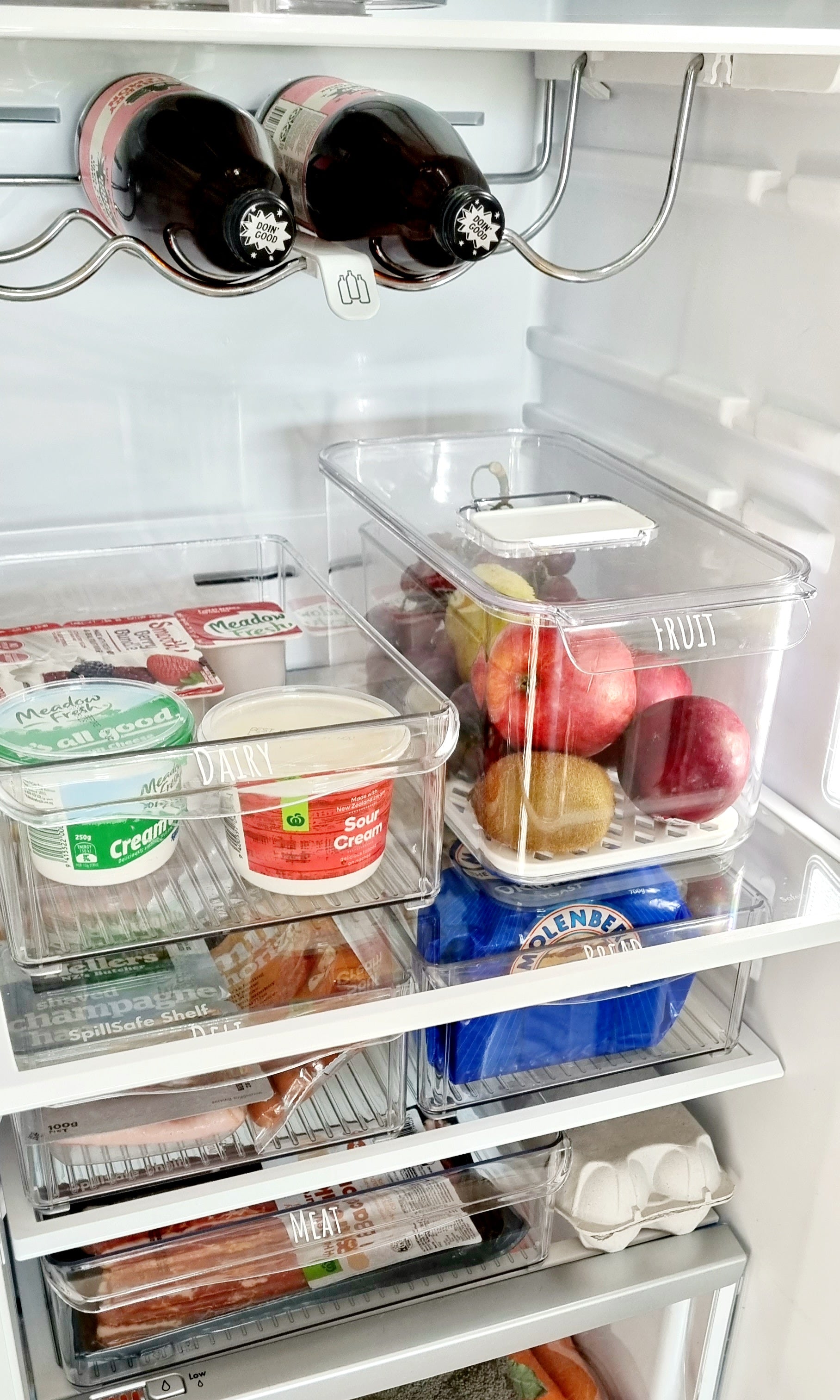 Organised fridge using trays and turntables for easy access and efficient fridge organisation, kitchen storage, and decluttering services NZ.