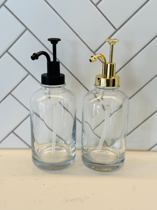 Two glass syrup dispensers with pump tops on a kitchen counter.