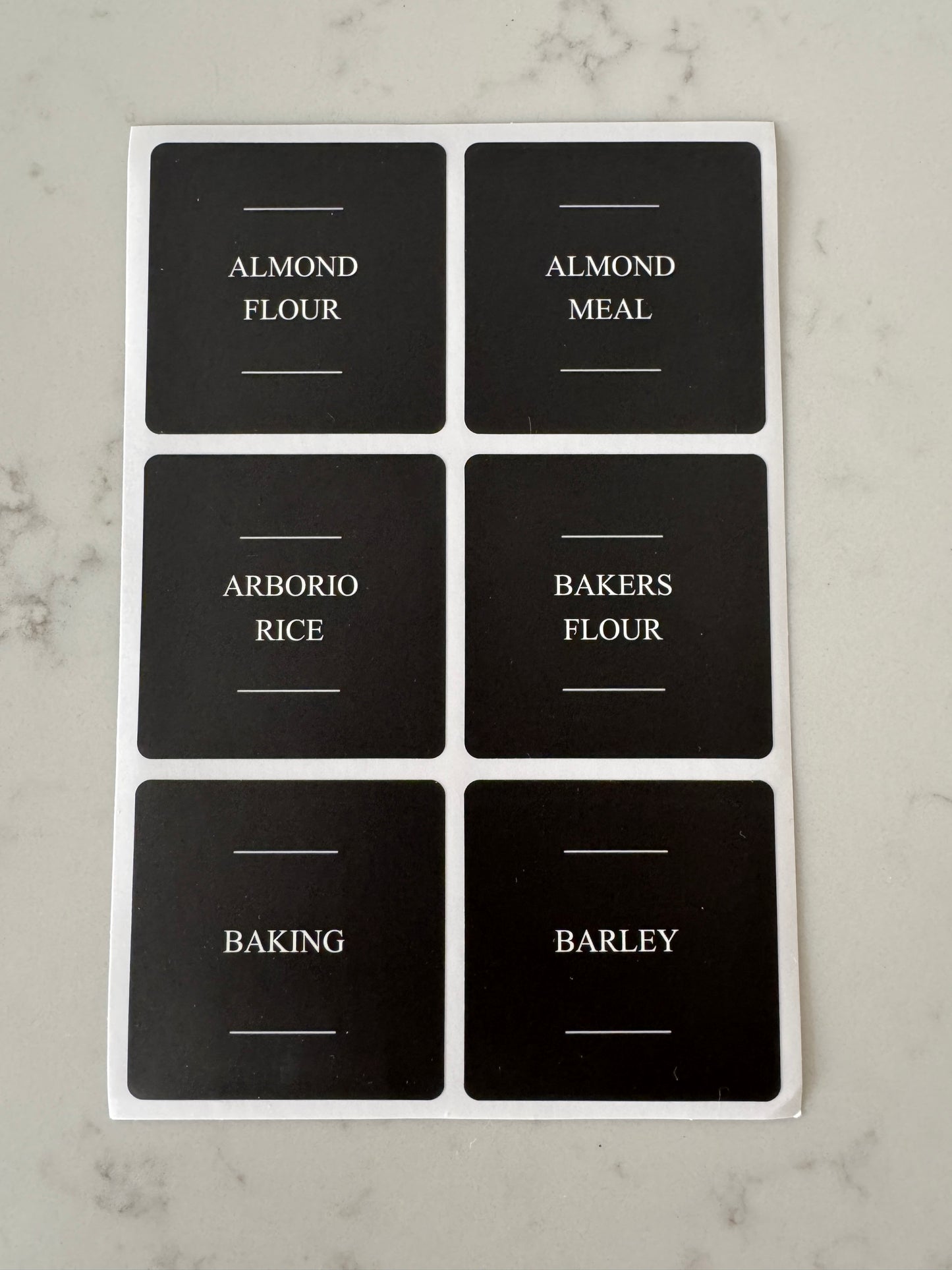 Set of black labels with white text on a marble surface