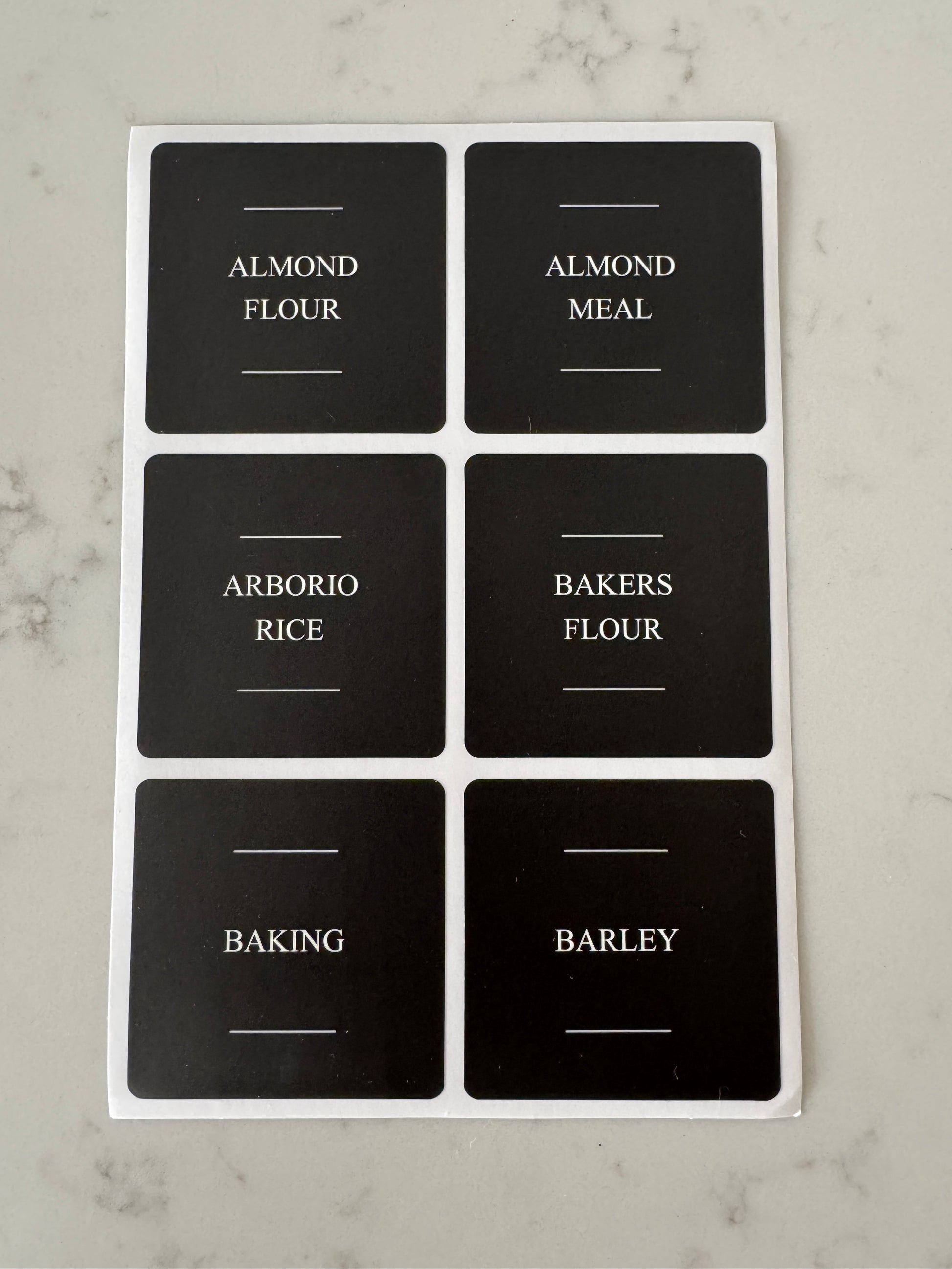 Set of black labels with white text on a marble surface