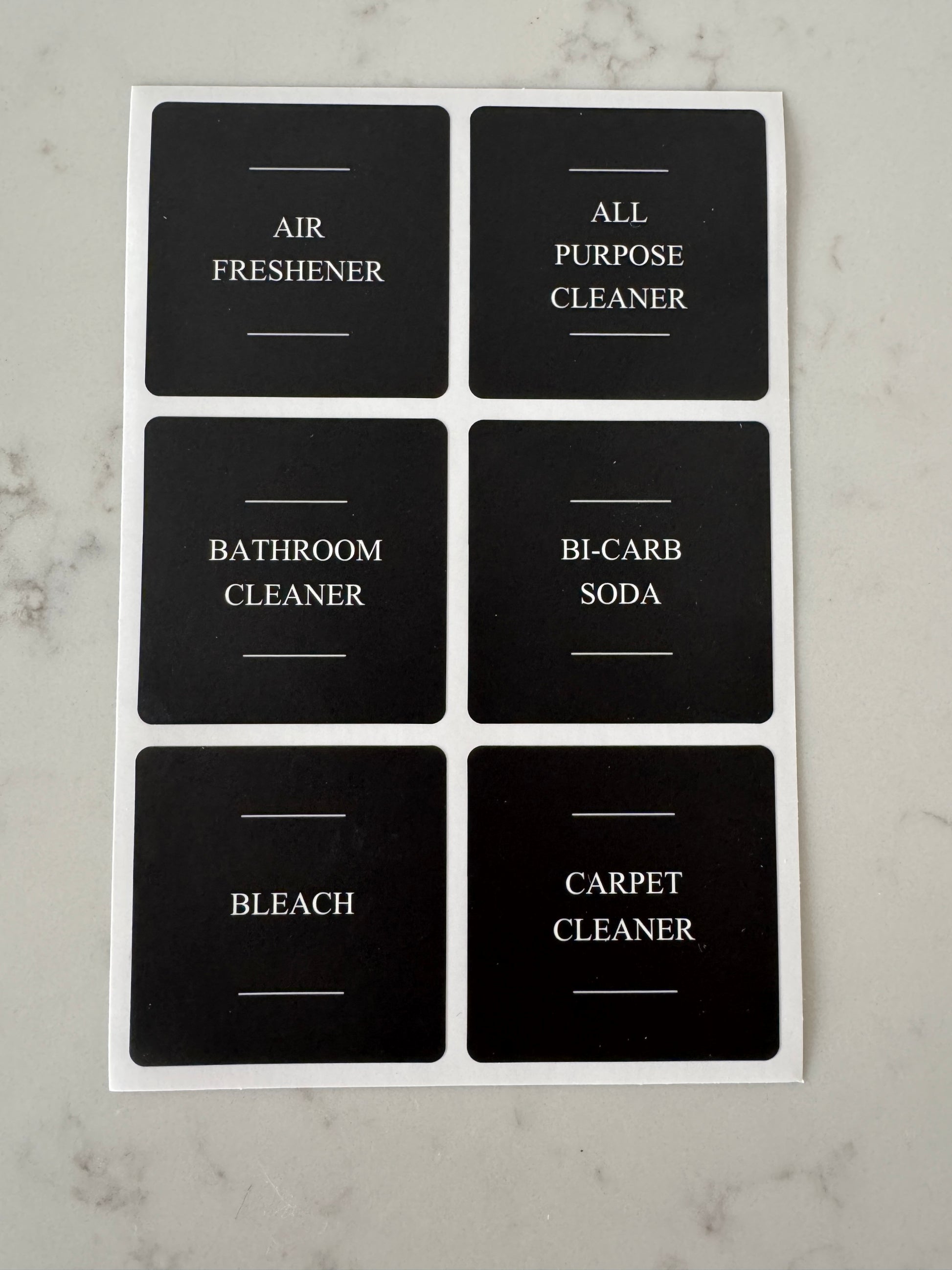 Set of black labels with cleaning product names on a marble surface