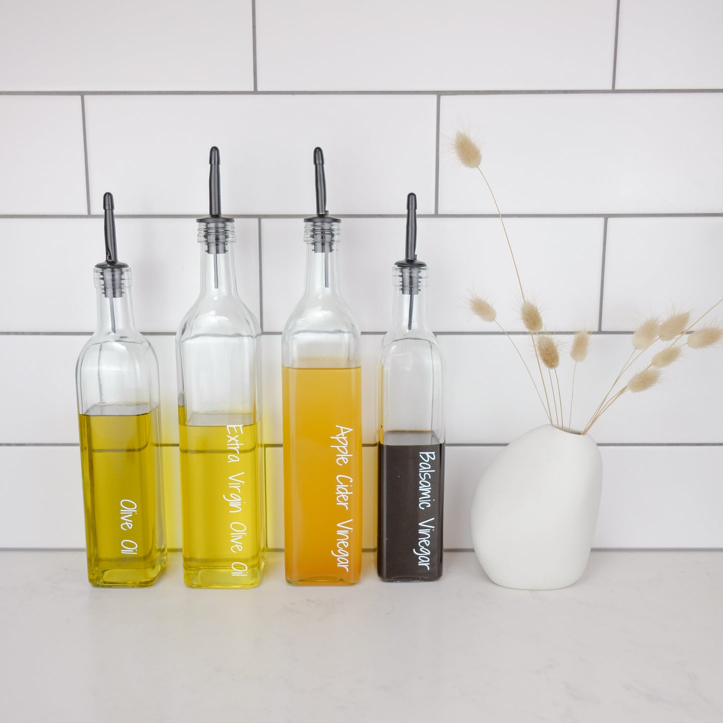 Glass oil bottles with black plastic pourers, ideal for kitchen storage and pantry organisation in NZ homes.
