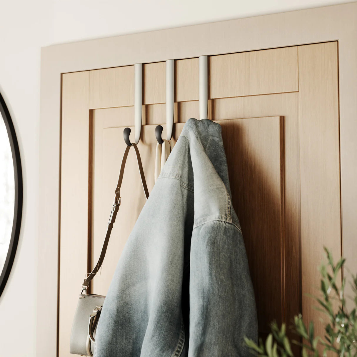 Denim jacket and bag hanging on over the door hooks.