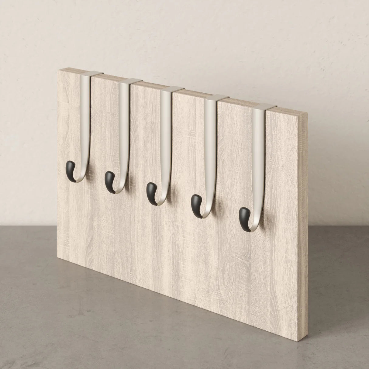 Wooden wall hook rack with five black hooks on a neutral background