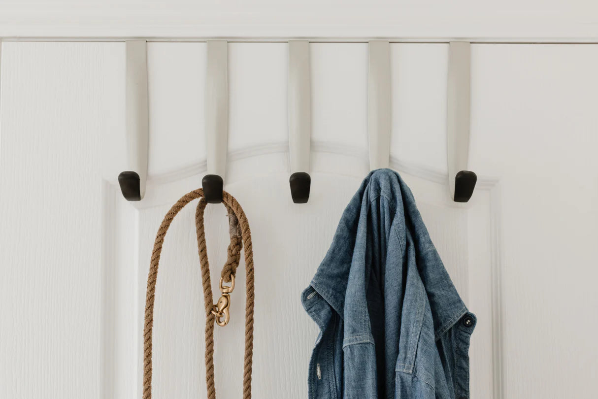 Set of five nickel-finish over-the-door hooks hanging on a door, used for organising clothes and accessories.
