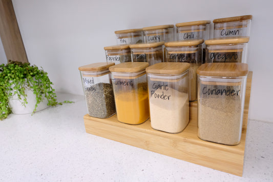 Glass spice jars on bamboo rack, ideal for pantry organisation, kitchen storage, and decluttering services NZ.
