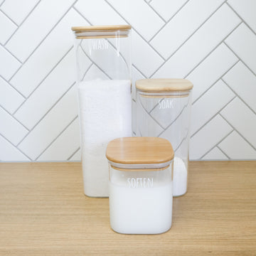 Square glass containers with bamboo lids, perfect for laundry organisation and home organisation services NZ.
