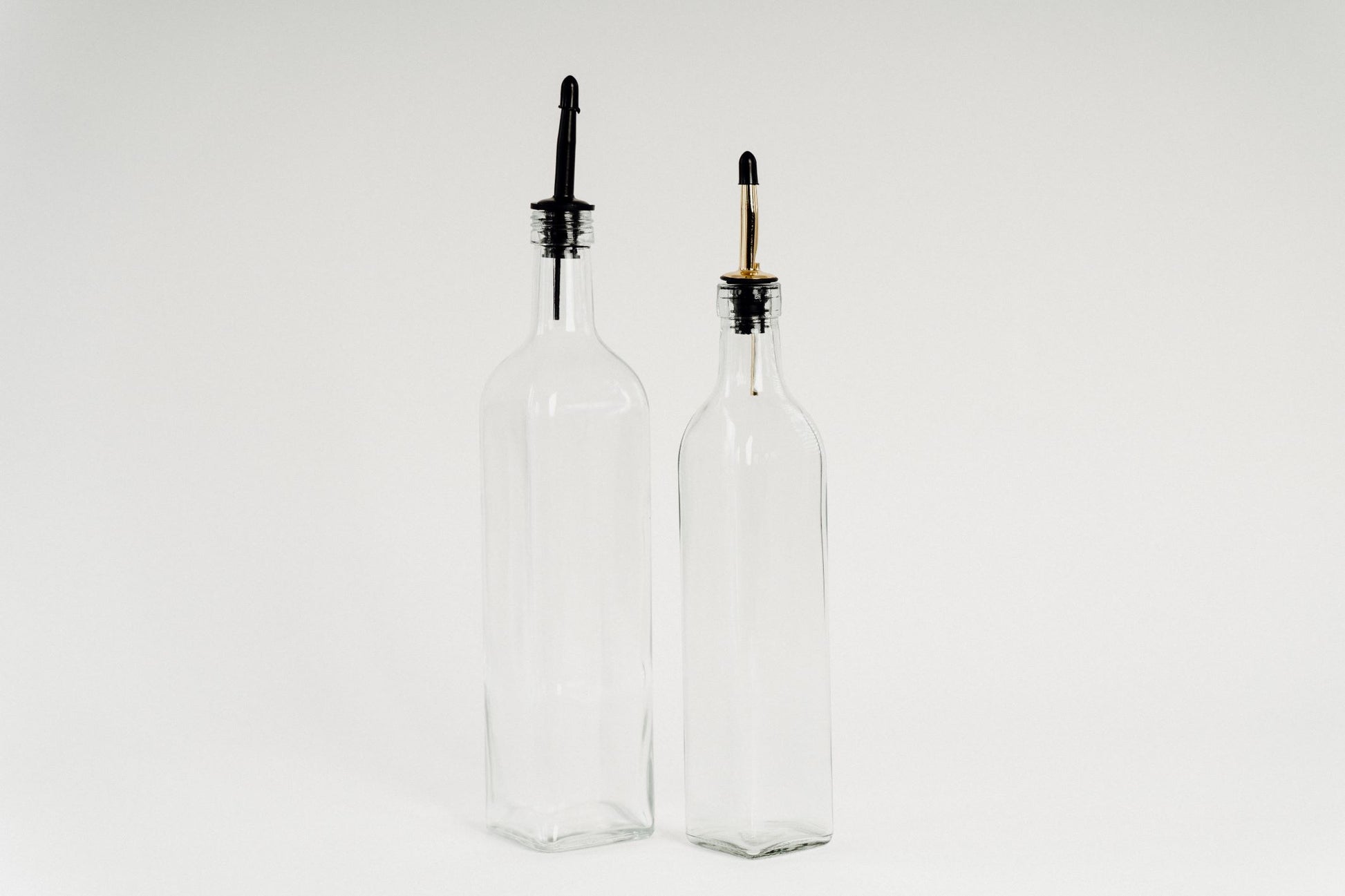 Glass oil bottles with black plastic pourers, ideal for kitchen storage and pantry organisation in NZ.
